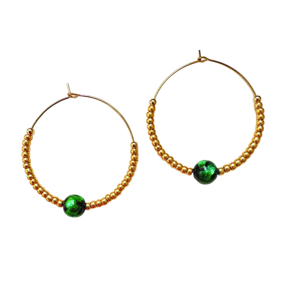 Ces créoles jouent sur la silhouette parfaite : cercle doré, touche verte vibrante, équilibre impeccable. Elles apportent ce détail mode qui fait toute la différence.